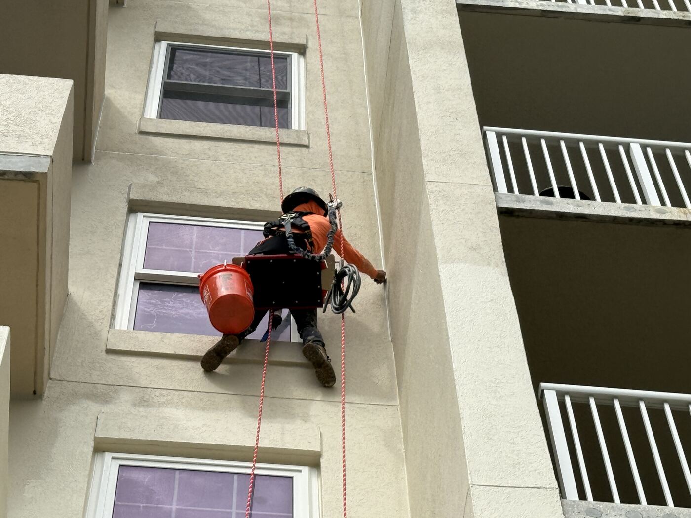 Rope access technician performing a building envelope evaluation on the Ocean Place facade