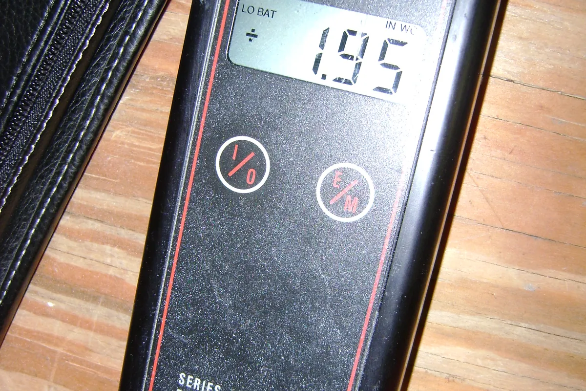 Digital pressure gauge display beside a window frame.
