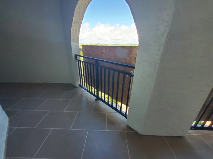 An installed black railing beneath a refinished arch, beside the new walkway coating. Temporary exterior protection remains.