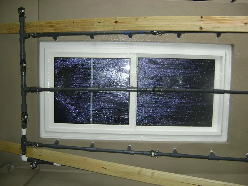 Spray rack of pipes and nozzles mounted over the exterior of a newly installed sliding window