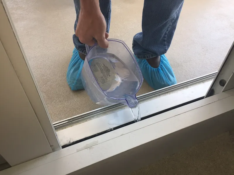 Water being poured into a temporary dam built at the sill of a sliding glass door