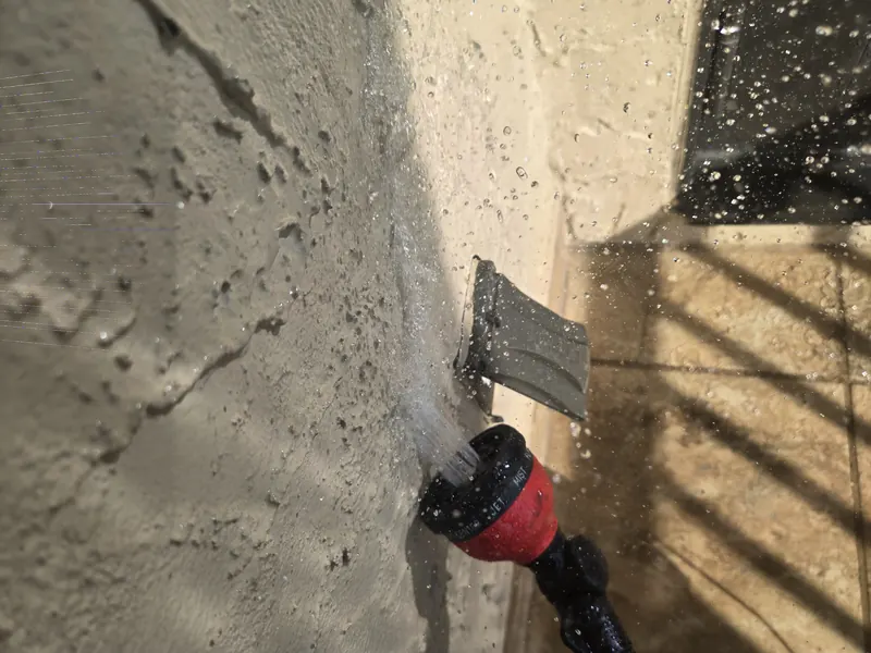 Spray nozzle directing water at a wall penetration in a stucco wall