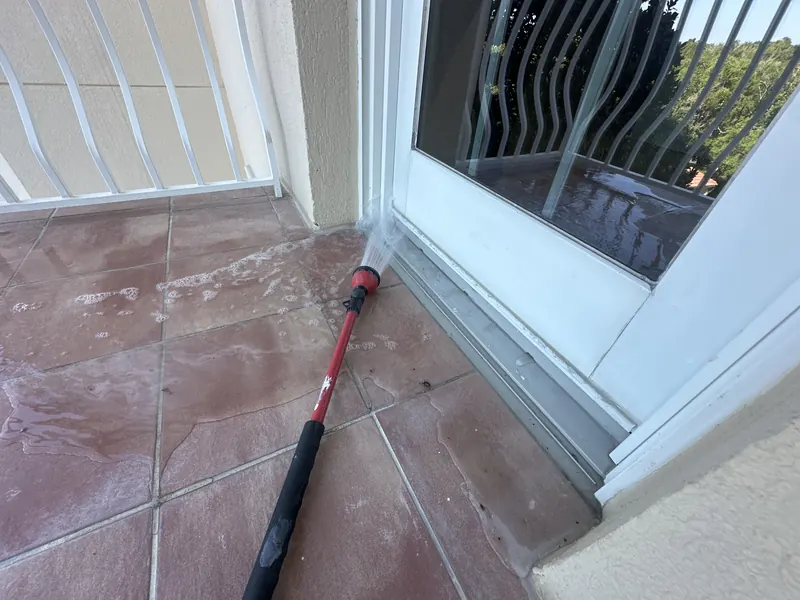 Spray wand directing water at the base of a balcony swing door during a water test